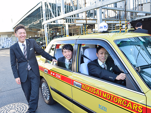 国際自動車（㎞タクシー）世田谷営業所所属のタクシードライバー、石垣さん、小野さん、高橋さんの笑顔の写真